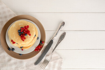 Wall Mural - Plate of sweet pancakes with fresh blueberries and red currants on white wooden background