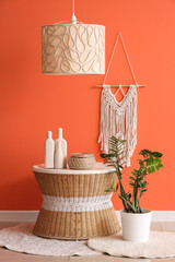 Wall Mural - Table and houseplant near orange wall in interior of living room