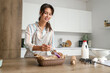 © Pixel-Shot - Young woman greasing raw poppy buns in kitchen
