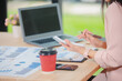 © ThawKyar - Smiling young Asian businesswoman is thinking and analyzing work plan in office hard using laptop, smartphone, calculator and documents. Chart sheet on table. Business and finance concept.