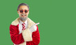 © Studio Romantic - Glad male Santa Claus dressed in red clothing, white gloves and stylish sunglasses, indicating index finger on copy space, showing place for advertisement or promotion, green background