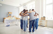 © Studio Romantic - Group of volunteers of different ages indoors standing in a circle hugging, view from the back. Employees of a charity fund before starting work. Concept homeless center, humanitarian project