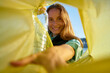© Westend61 - Smiling volunteer putting plastic bottles in yellow garbage bag