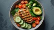 © Lasvu - Fresh grilled chicken breast with avocado, cherry tomatoes, cucumber, and spinach in a bowl.