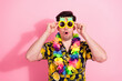 © deagreez - Colorful man wearing tropical shirt and pineapple glasses posing on a pink background celebrating summer fun.