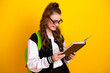 © deagreez - Charming female student wearing stylish sportswear and reading a book against a bright yellow background