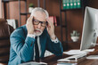 © deagreez - Senior businessman in frustration at his office desk with a computer, wearing formal suit, contemplating and problem-solving