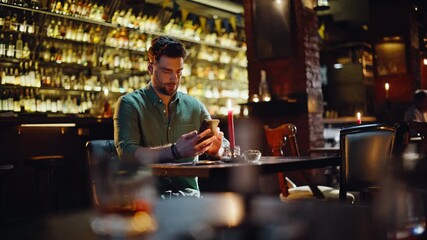 Man using smartphone bar. Bearded guy browsing cellphone screen sitting alone