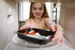 © YarikL - Smiling girl putting ready meal tray into microwave oven, view from inside the appliance.