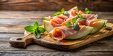 Thinly sliced Italian cured ham served on a rustic wooden cutting board with fresh melon and mint , prosciutto, fruit,  prosciutto