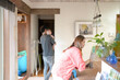 © Masakazu Tokashiki - In a Mediterranean-style living room, a Japanese man in his 30s walks holding a 3-month-old baby while a mother in her 20s wearing orange cleans the table. Japan. Summer.