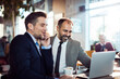 © Davor - Two businessmen discussing work over laptop in coffee shop