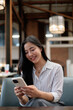 © PaeGAG - Young Asian businesswoman using mobile phone in modern office space