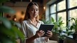 © Arip - Focused Professional A Woman with a Tablet in a Bright, Plant-Filled Workspace