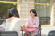 © Masakazu Tokashiki - Two women sitting at a table outside a restaurant, one of them smiling. The other woman is holding a cup