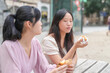 © Masakazu Tokashiki - Two women sitting at a table eating food. One of them is wearing a pink shirt. Scene is casual and relaxed