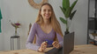 © Krakenimages.com - Woman smiling with credit card in hand and using laptop at home in modern living room showing positivity and online shopping in casual environment.