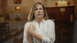 © Krakenimages.com - Woman clutches chest with both hands, eyes closed in church aisle near wooden pews under warm chandelier light; pain.
