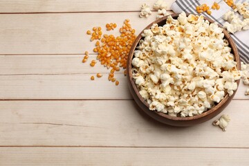 Wall Mural - Tasty popcorn and corn kernels on light wooden table, flat lay. Space for text