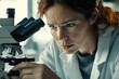 © Imagehub - A focused female scientist meticulously examines a sample under a microscope in a laboratory setting.