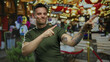 © Krakenimages.com - Young man with tattoos smiling and pointing at a festive outdoor market setting.