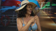 © Krakenimages.com - Hispanic middle-aged woman wearing a bikini and sun hat enjoys a restful moment on a boat under soft lighting at seaside.