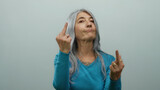 Senior woman with grey hair smiling while making a rude gesture with both hands against a white background, displaying attitude and defiance in an isolated setting.