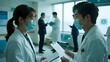 © Big - Medical professionals in a hospital setting, discussing patient records while wearing protective masks.