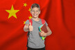 © New Africa - Little boy with backpack and notebooks showing thumbs-up against flag of China. Language school