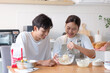 © wattana - Happy couple making dough together in a cozy kitchen, smiling and enjoying the baking process.
