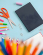 © Sergey - Flat lay of colorful school stationery including scissors, pencils, markers, paper clips, and a notebook on a light blue background, blurry foreground. isolated with white highlights