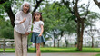 © wattana - Senior woman and little girl enjoy quality time walking together in a green park.