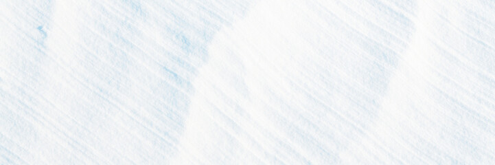 Wall Mural - Wide panoramic winter background with snowy ground. Natural snow texture. Wind sculpted patterns on snow surface.