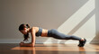 © Lexi - Young woman performing plank exercise on wooden floor indoors
