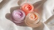 © rinz - Three jars of different colored face creams on a soft, white fabric