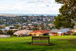 © Doublelee - Park bench overlooking suburban houses and a wide cityscape view towards the bay in Highton, Geelong, Australia. A peaceful lookout point combining residential living with scenic natural surroundings.