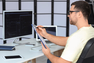 Portrait of male programmer with clipboard in office