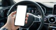 © Djemari - Close-up of a person's hand holding a blank smartphone screen inside a car.