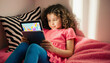 © jack - Cute Little Girl Lying on Bed Using a Tablet