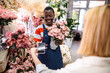 © Jelena - Florist accepting payment via smartphone from customer in flower shop