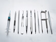 © Bakul - Collection of polished stainless steel medical instruments and syringe on white background surgical tools
