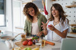 © Dorde - Two Young Women Joyfully Cooking Together in a Bright Modern Kitchen with Fresh Ingredients