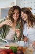 © Dorde - Smiling Young Women Friends Cooking Together in a Bright Modern Kitchen with Fresh Ingredients