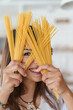 © Dorde - Smiling Young Caucasian Woman in a Bright Modern Kitchen Holding Uncooked Spaghetti