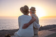 © luciano - Back view of serene couple of seniors sitting face the sea at dusk, elderly caucasian people looking at horizon over water enjoying vacation or retirement