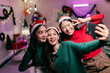 © Parichat - Asian friends taking selfie with christmas hats and making funny faces
