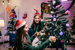 © Parichat - Two happy young women decorating christmas tree at home