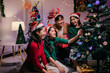 © Parichat - Group of Friends Decorating Christmas Tree Together at Home