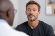 © SerPak - A man with a beard is having a conversation with a healthcare professional in a clinical setting, conveying a sense of trust and openness.