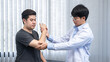 © Ngampol - Young asian physiotherapist giving assistance to man patient with elbow injury